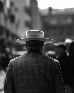 greyscale photo of man wearing hat near people thumbnail