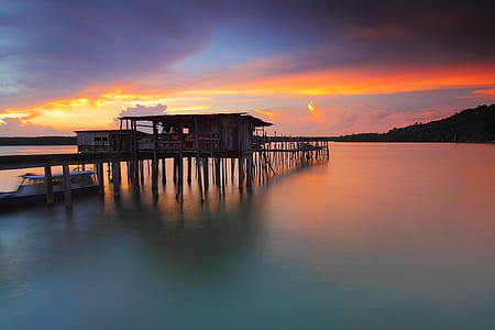 silhouette photography of sea dock on body of water thumbnail