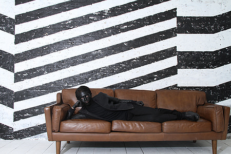 man lying on brown leather 3-seat sofa thumbnail