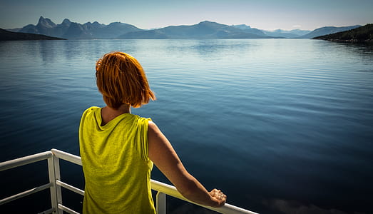 person holding on fence facing body of water thumbnail