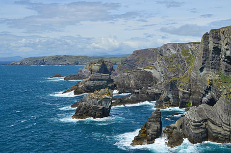 aerial photography of brown rock formations and seawaves at daytime thumbnail