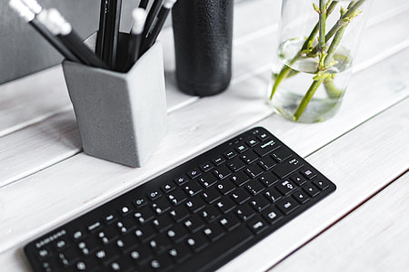 Black keyboard with pencils on a white table thumbnail