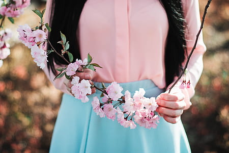 woman in pink long-sleeved shirt holding pink flower thumbnail