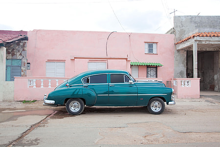 photo of blue sedan beside pink house thumbnail