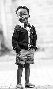 grayscale photo of boy standing on road thumbnail