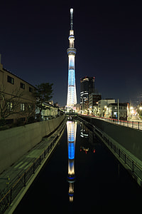 architectural photo of gray concrete tower in city skyline during nighttime thumbnail