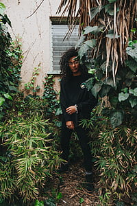 man in black long-sleeved top surrounded by plants thumbnail
