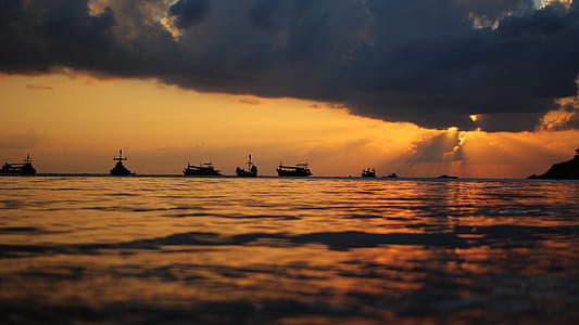 silhouette photography of sailboats on sea during golden hours thumbnail
