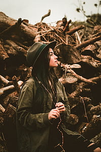 shallow focus photograph of woman beside tree logs thumbnail