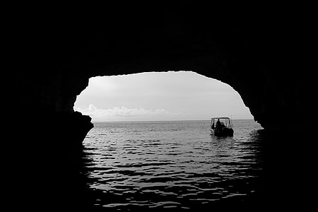 photo of boat on calm body of water going inside cave thumbnail