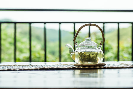clear glass teapot with green liquid on round brown tablet cloth thumbnail