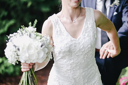 woman wearing white lace V-neck sleeveless wedding dress holding her groom thumbnail