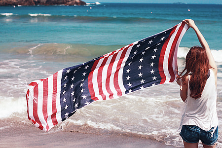 woman in white tank top holding USA flag thumbnail