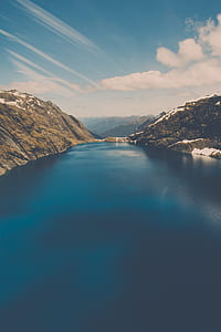 body of water and snow-covered mountains during daytime thumbnail