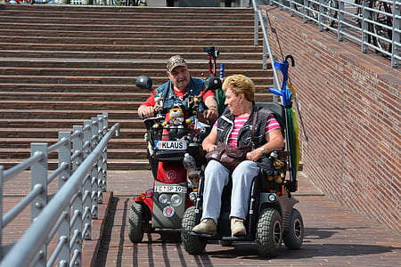 man and woman riding power chairs thumbnail