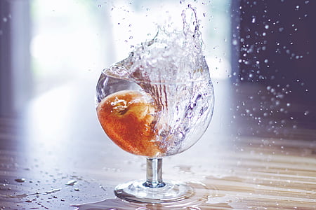 fruit drop on water filled drinking glass spilling water on brown surface thumbnail