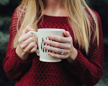 woman wearing red sweater holding white ceramic mug thumbnail