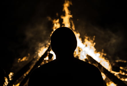 silhouette photography of person standing near fire thumbnail