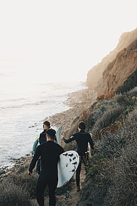 three men holding surfboard walking towards sea thumbnail