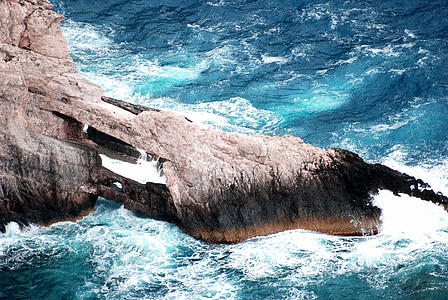 sea waves crashing on brown rock formation thumbnail