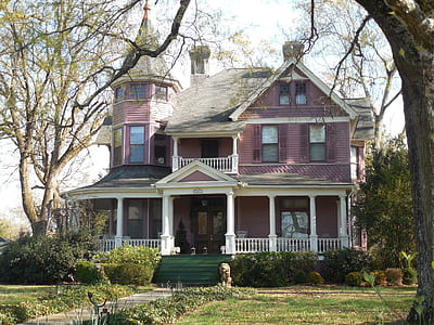 pink and white wooden house surrounded with grass and trees thumbnail
