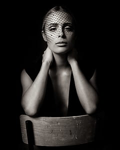 sitting woman in sleeveless top with net headdress in dark room thumbnail