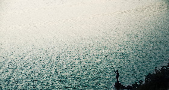 person using fishing rod near body of water thumbnail