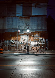 woman wearing gray long-sleeved shirt with black pants walking on street light during night time thumbnail