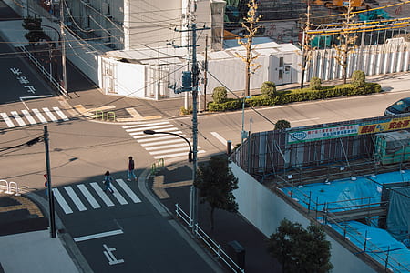 street photography of two persons walking on cross road near buildings thumbnail