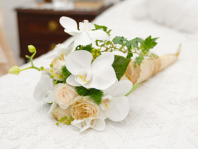 white and green flower bouquet on white bed thumbnail