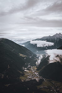 aerial photography of buildings below mountains under gray sky thumbnail