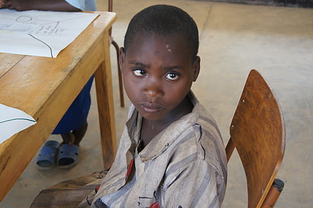 boy sitting on brown wooden chair near table thumbnail