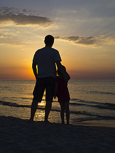 silhouette of man and girl on beach watching sunset thumbnail