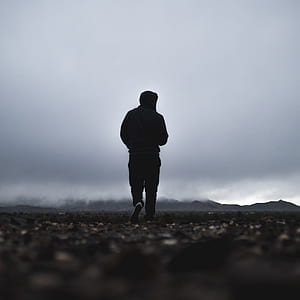 silhouette of person wearing black hoodie under cloudy sky thumbnail