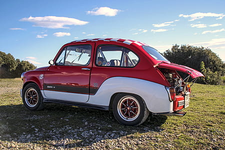 classic red and white 3-door hatchback on field during daytime thumbnail