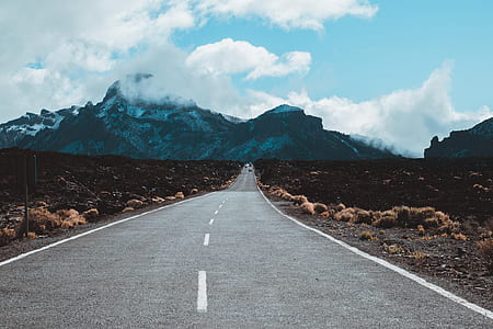 gray concrete road towards mountain at daytime thumbnail