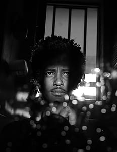 grayscale photo of curly-haired man looking at window thumbnail