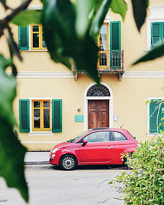 red FIAT 500 3-door hatchback parked beside concrete building thumbnail