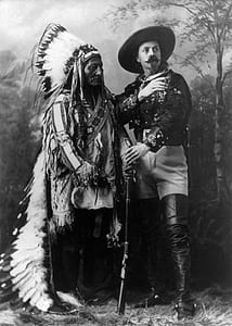 grayscale photography of Native American man standing next to man wearing hat thumbnail