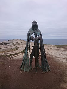 man in robe holding sword statue near cliff thumbnail