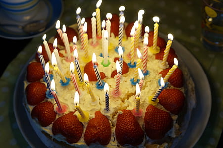 white icing cake with strawberry topping and in-lighted candles thumbnail
