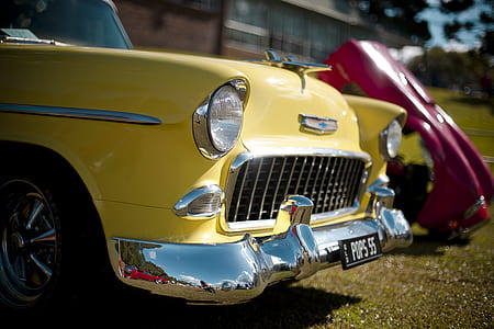 classic yellow Chevrolet parked beside red car thumbnail