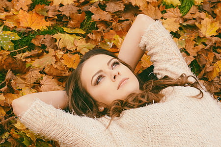 Woman in Sweater Laying on Dried Maple Leaves thumbnail