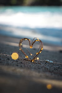 shallow focus photography of heart-shaped brown twig on brown sand thumbnail