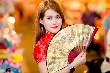woman in red top holding hand fan while smiling thumbnail