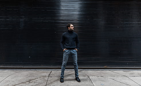 man standing beside black roll-up door thumbnail