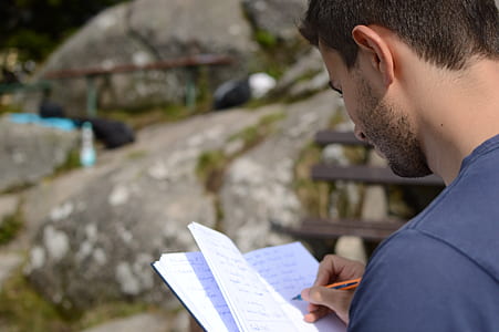 person holding notebook while writing at daytime thumbnail