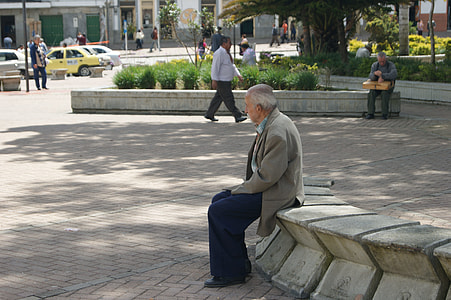 shallow focus photography of man in gray formal suit jacket sitting on gray concrete bench during daytime thumbnail