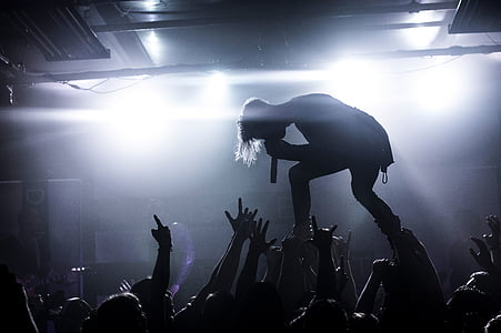 silhouette of mail singer on stage in front of crowd thumbnail