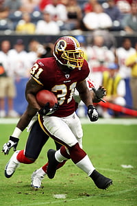 selective focus photography of person playing football holding ball on field at daytime thumbnail